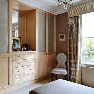 dressing room with buttery pale cupboards mirror and chair