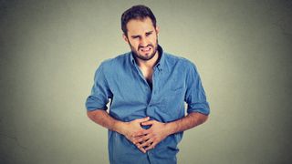 Man in discomfort holding his stomach