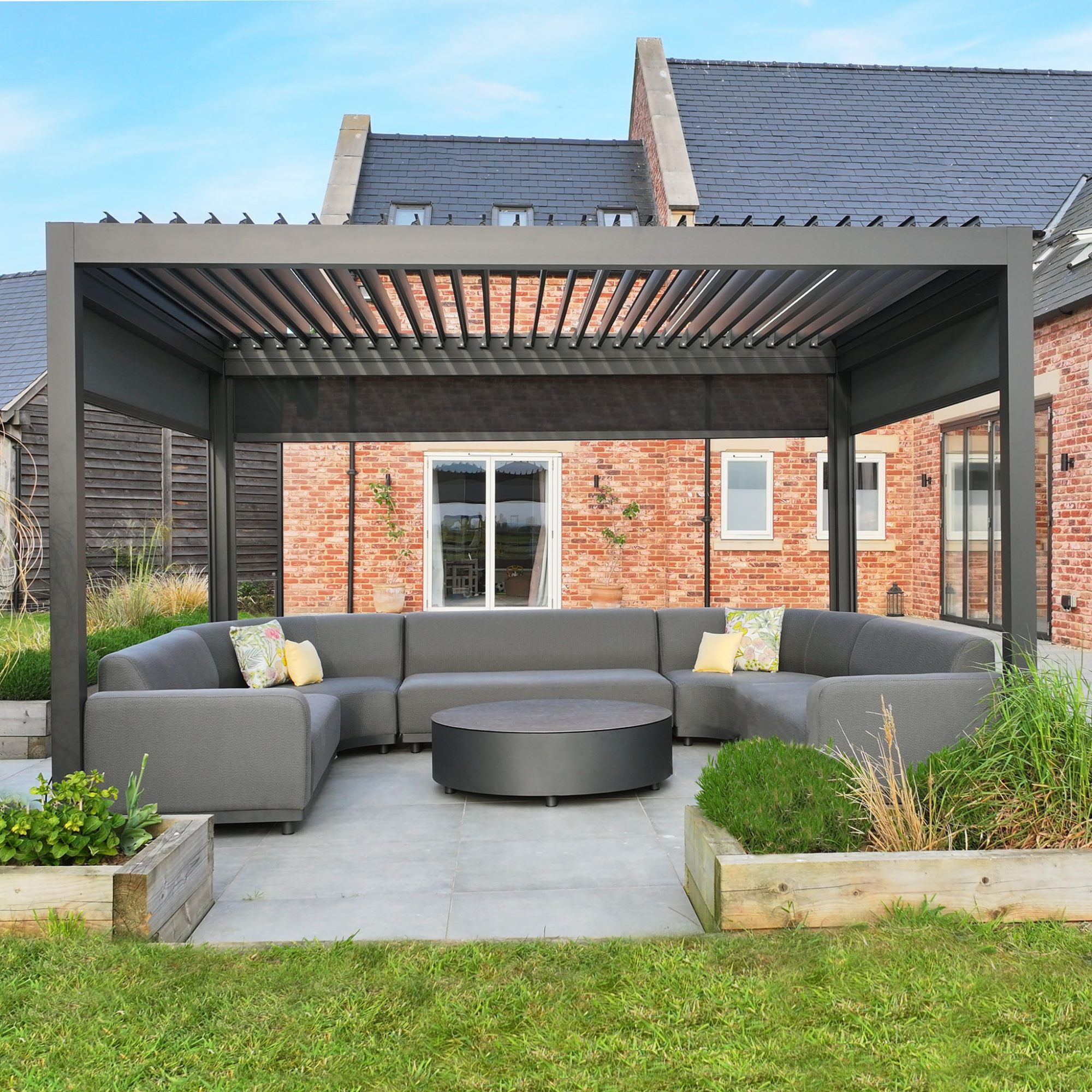 An aluminium pergola with louvre roof, decked out with furniture