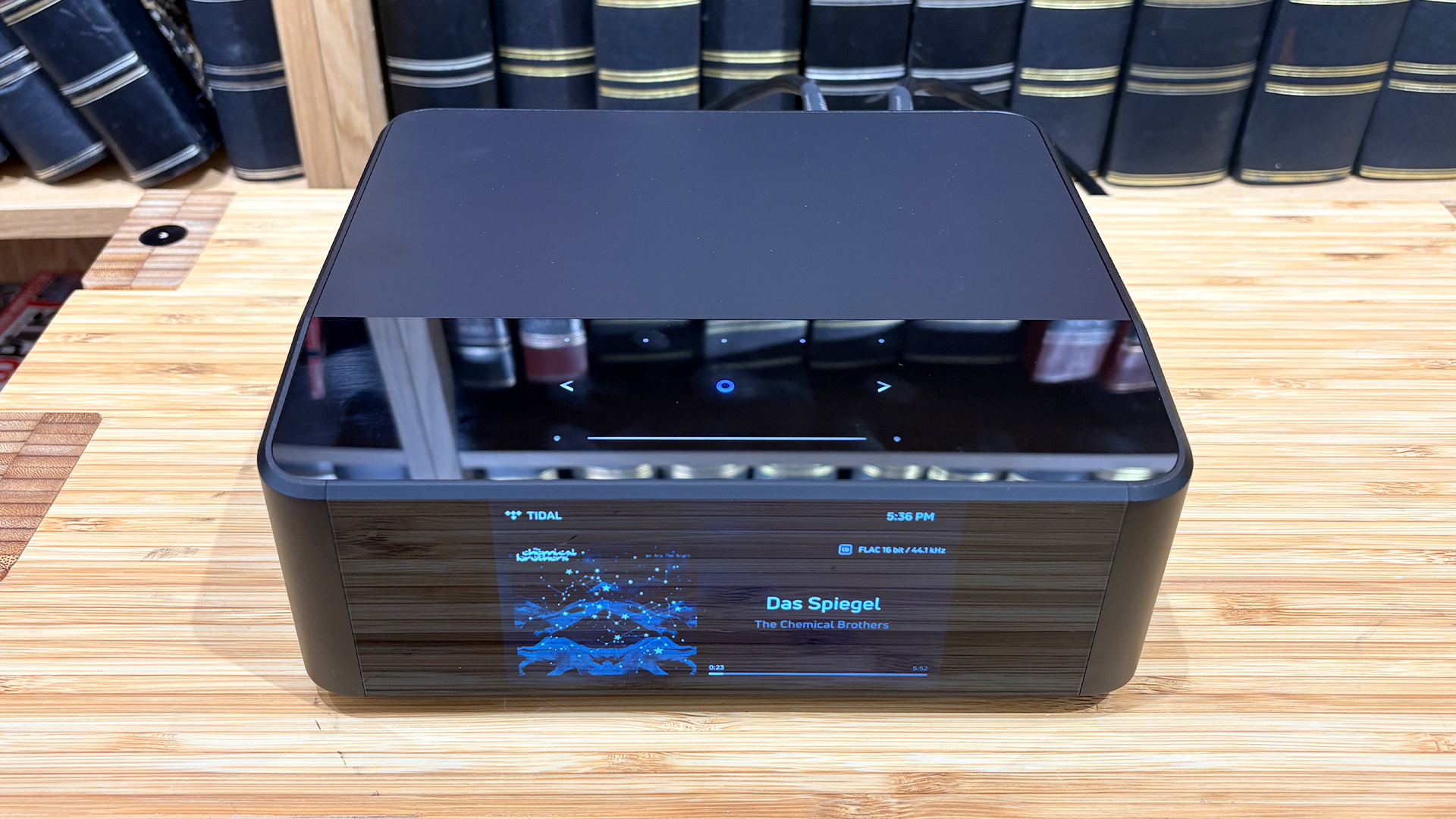 Bluesound Node Icon music streamer on wooden hi-fi rack in front of bookcase slight elevation to shot