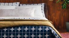 Bedroom with wooden panelled wall and white, blue and yellow bedding scheme