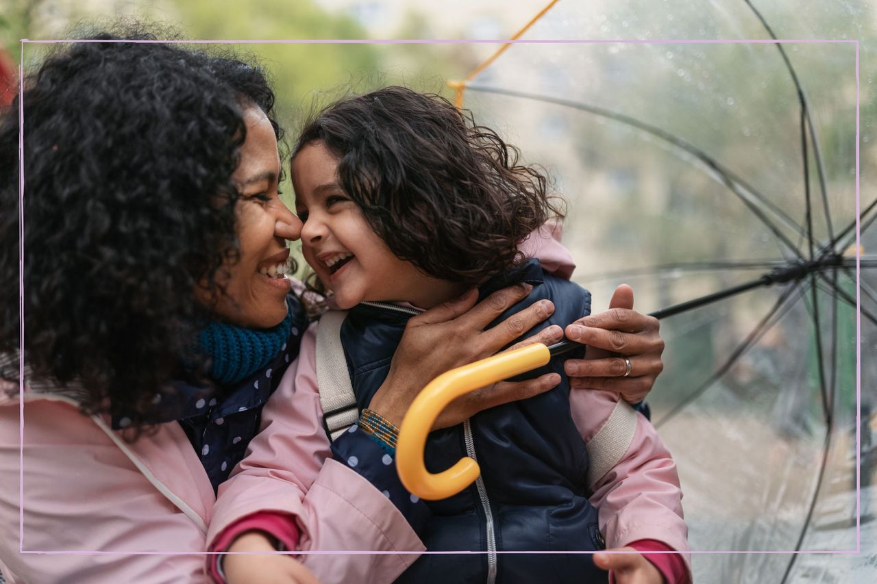 Mother and daughter sharing affectionate moment outside under clear umbrella