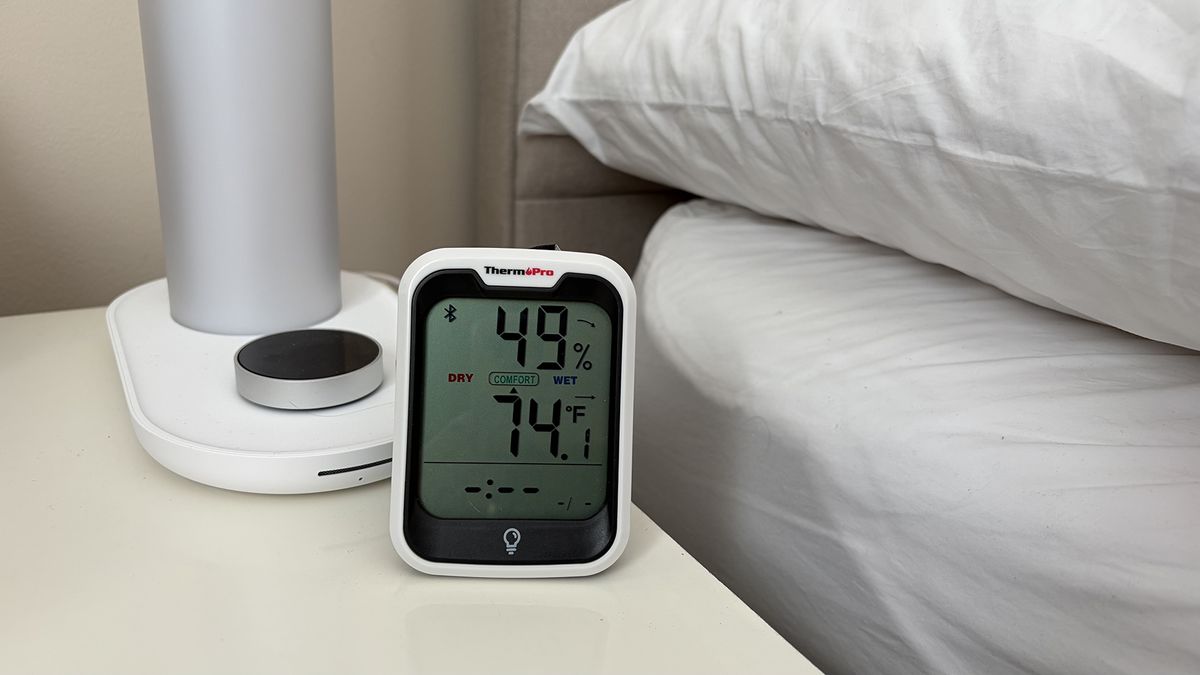 A close up of a room thermometer on a nightstand next to the Sleepal AI Lamp