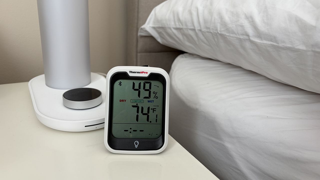 A close up of a room thermometer on a nightstand next to the Sleepal AI Lamp