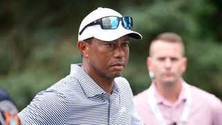 Tiger Woods looks on wearing a white cap and blue reflective sunglesses on his head at the 2024 US Junior Amateur