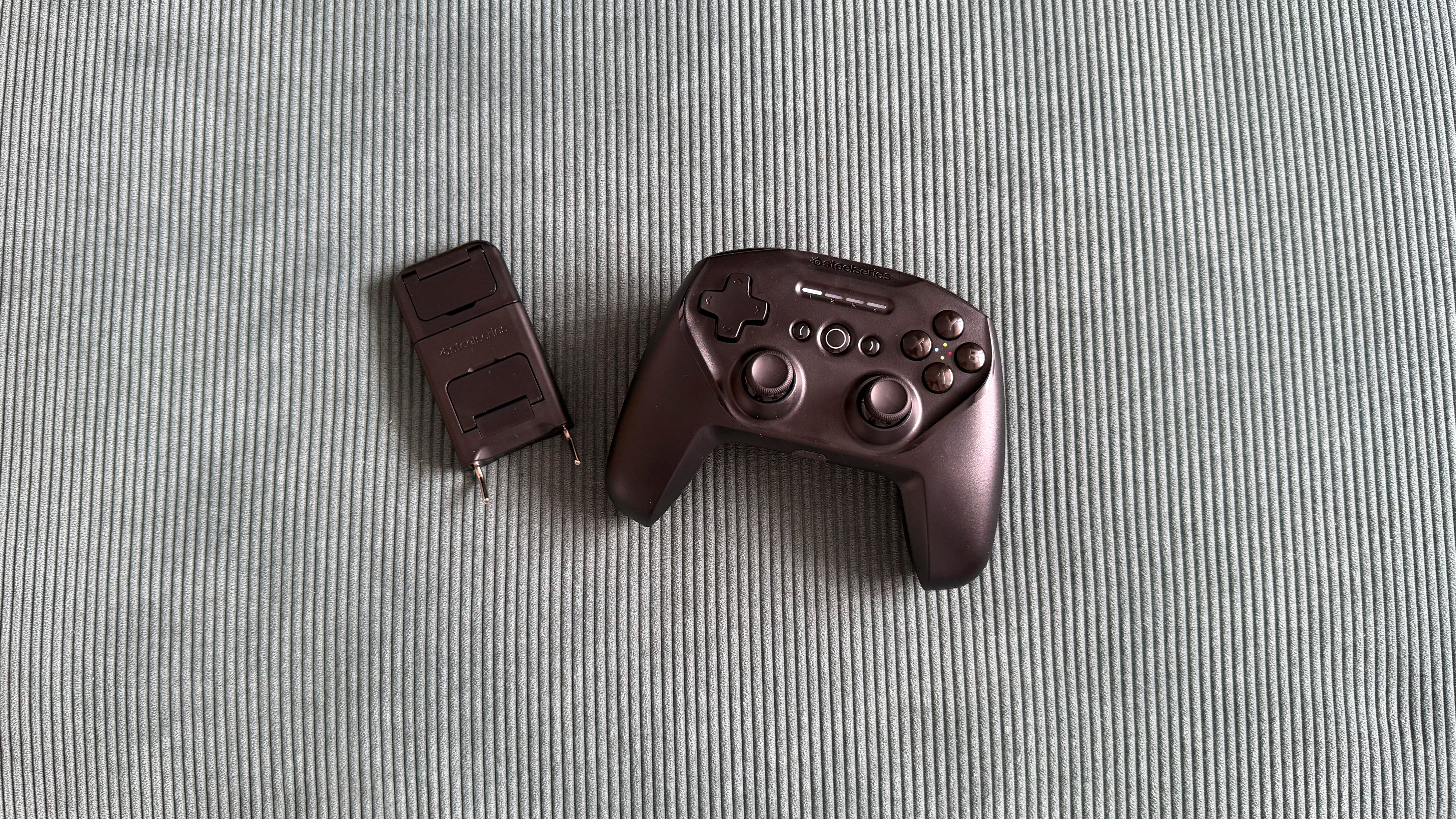 The SteelSeries Stratus+ mobile and PC controller on top of a green carpet surface