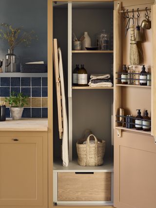 utility closet with ironing board, basket and cleaning products inside