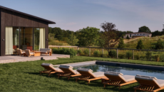 in-ground pool surrounded by grass and lined with five chaise lounge chairs