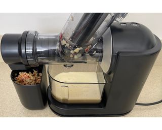 Philips Viva Masticating Juicer with apple juice yield and pulp container showing apple fiber