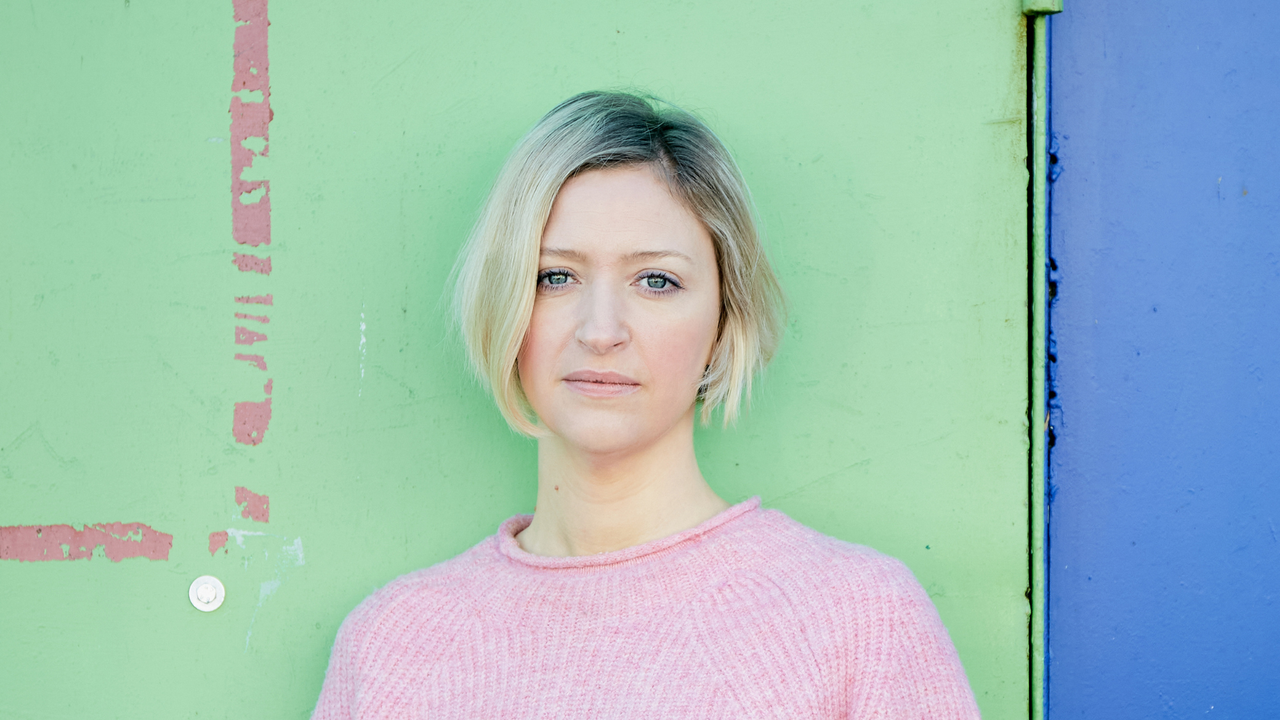 Psychologist and author Lucy Foulkes against a pale green wall.