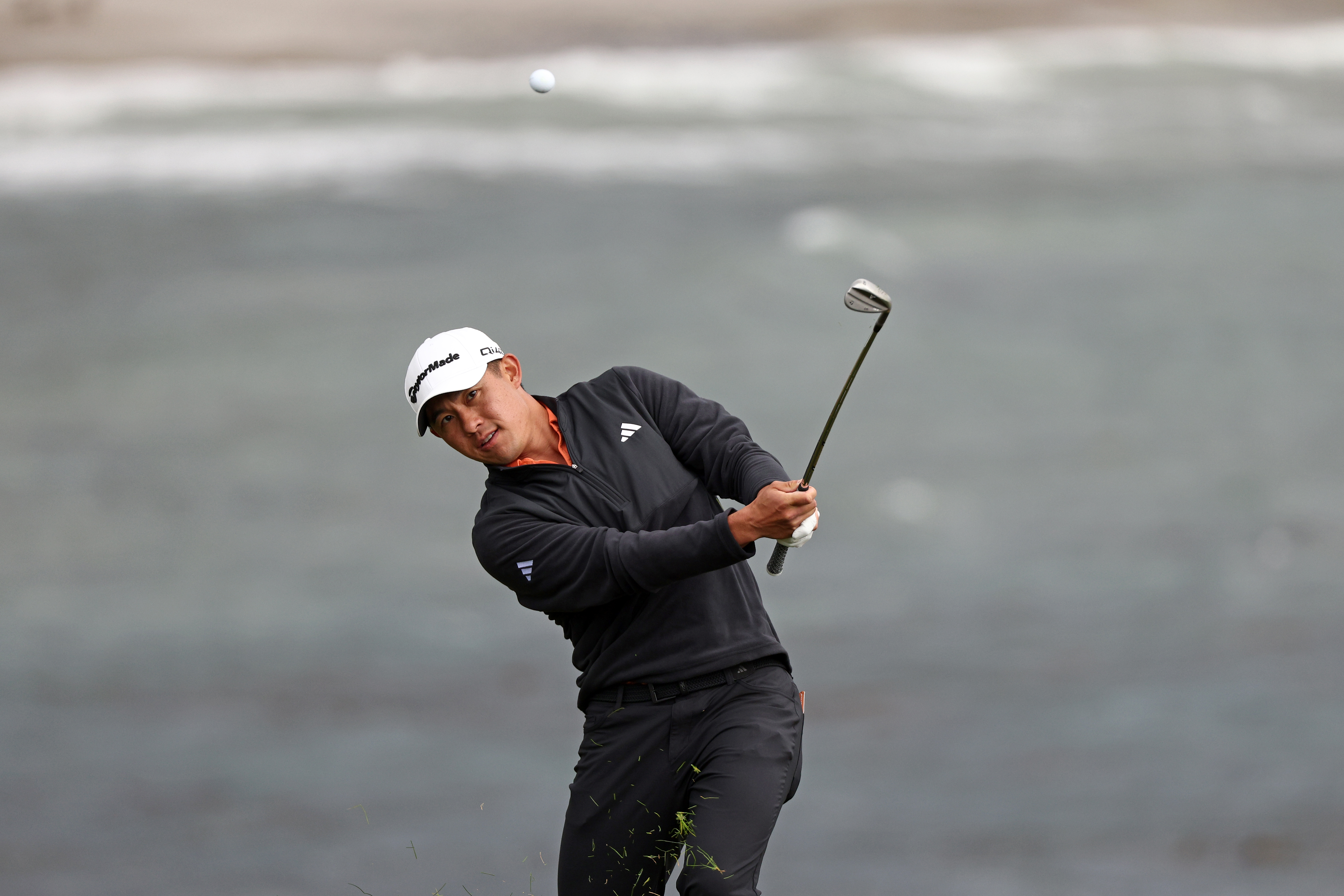 Collin Morikawa hits a wedge shot from the rough