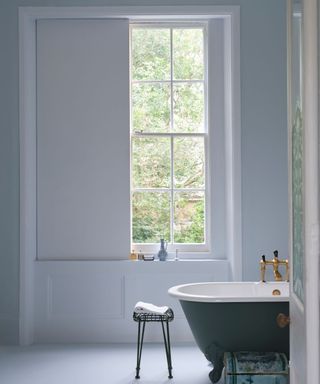 light and airy bathroom with pale blue walls and large window