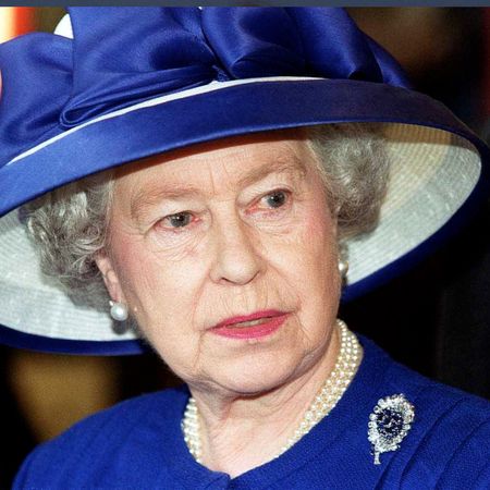 Britain's Queen Elizabeth II during a visit to Fitzalen High School wearing a royal blue suit with a matching wide-brim hat, a pearl necklace, and a sapphire and diamond brooch