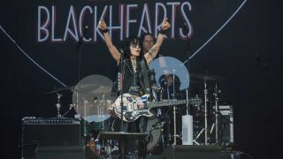 Joan Jett onstage raising her arms aloft