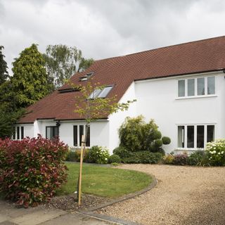 house with white wall trees grass and sky