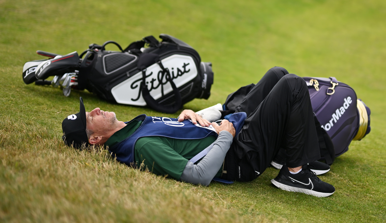 Ted Scott lies on the ground with his hand on his stomach