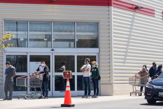 People wearing masks and keeping their distance from one another while waiting in line outside Costco in Wheaton, Maryland. 