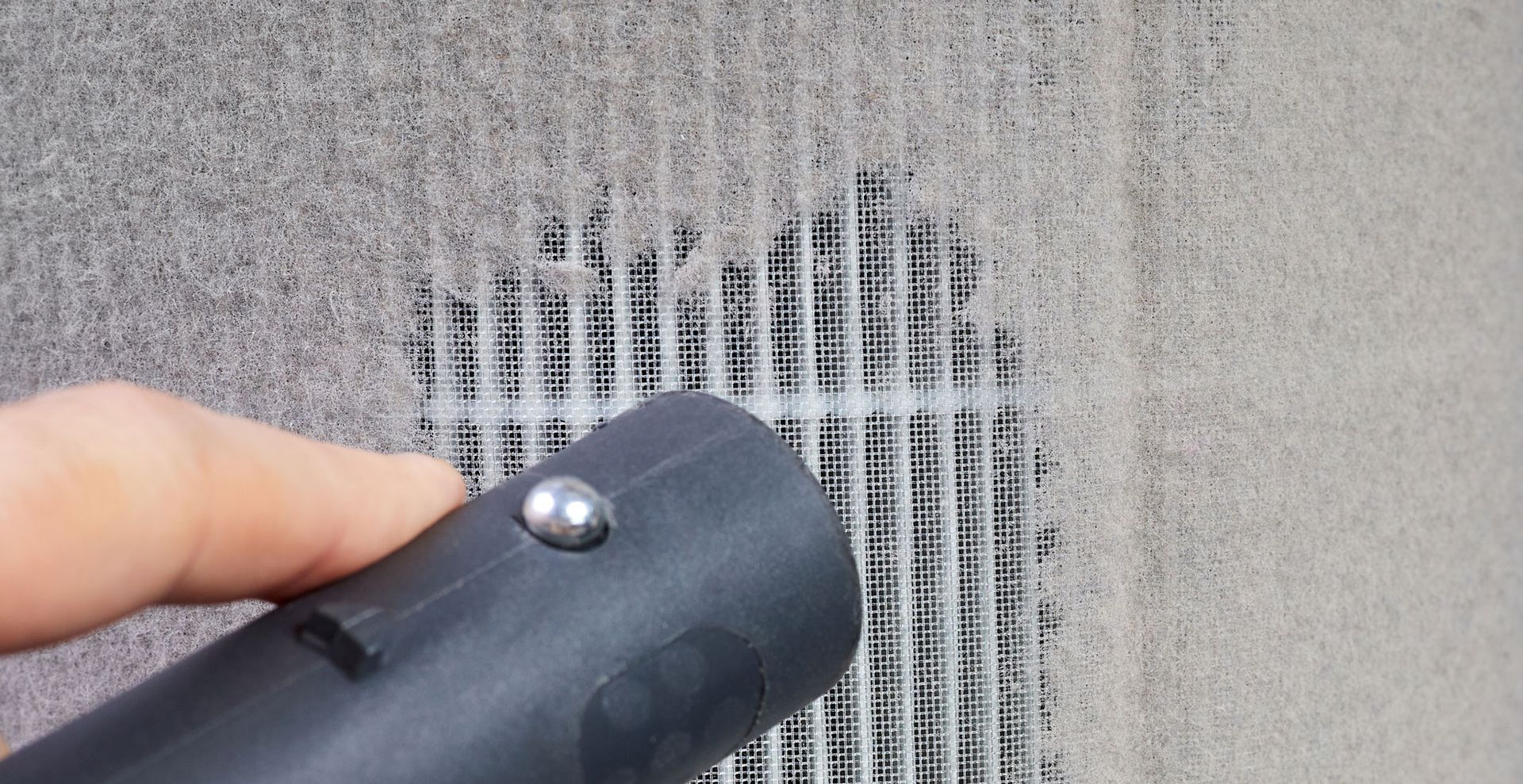 vacuum nozzle cleaning a filter to show a crucial step when looking how to clean a dehumidifier