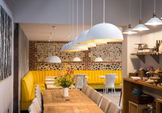 dining area with dining table and yellow seats and hanging lights