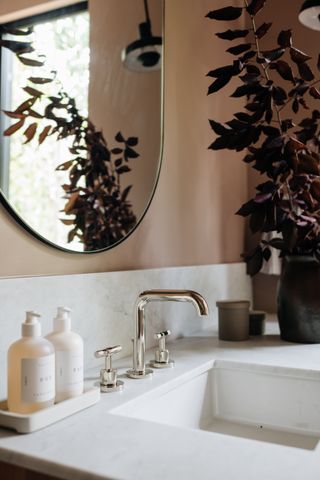 cozy bathroom with nickel taps, fall foliage and round mirror