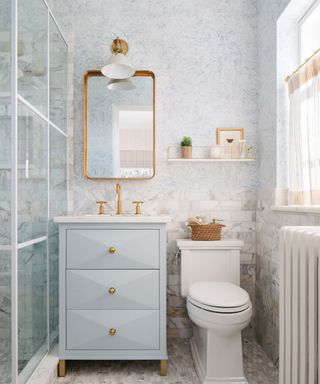 A small, light-blue bathroom with vanity and shower