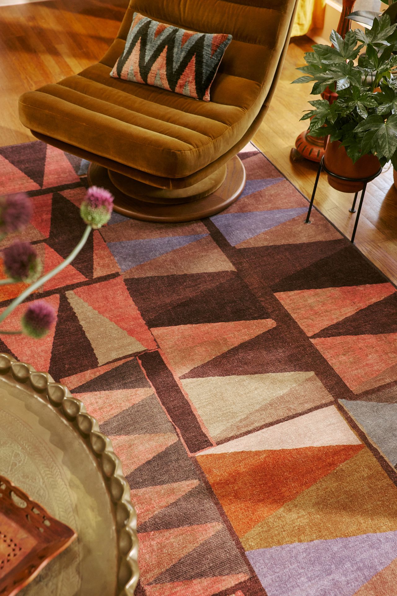 Close-up of a brown, pink, orange, and purple geometric rug with an ochre accent chair.