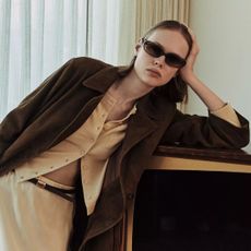 Vince spring 2026 collection look book with model in sunglasses, a yellow cardigan, brown jacket, and yellow satin skirt