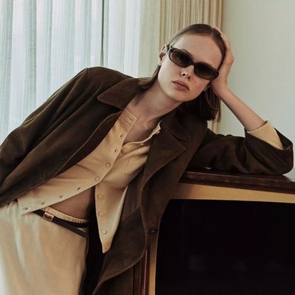 Vince spring 2026 collection look book with model in sunglasses, a yellow cardigan, brown jacket, and yellow satin skirt
