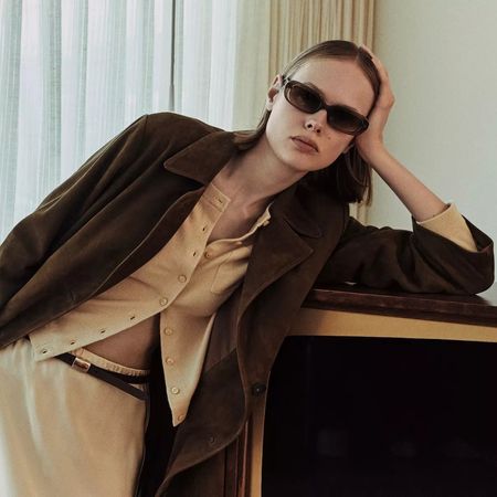 Vince spring 2026 collection look book with model in sunglasses, a yellow cardigan, brown jacket, and yellow satin skirt