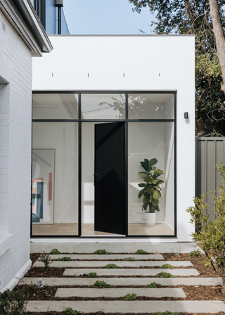 A stone tiled walkway leading to a black front door