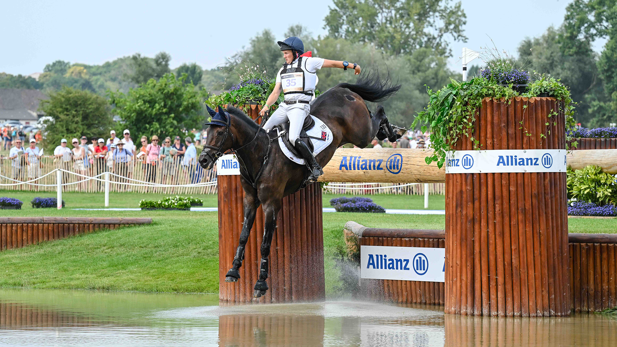 Tom McEwen "hails a cab" with just one hand on the rein as JL Dublin jumps over a hanging log into one of the water fences on the eventing World Championships cross-country course at Aachen