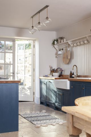 kitchen with blue cabinetry cream walls and pendant lights