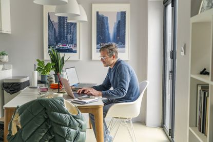 Side view of a man working from home from the dining table