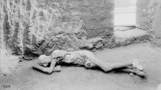 A black and white photo of a body cast of a person lying on the ground