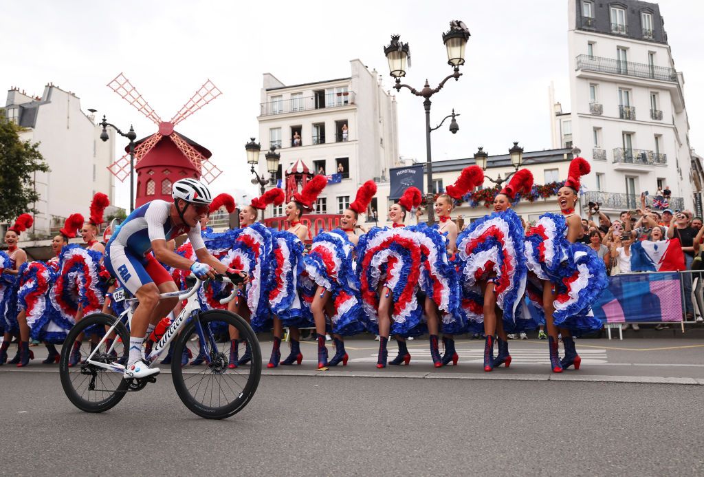 PARIS FRANCE AUGUST 03 Valentin Madouas of Team France competes passing through the Moulin Rouge with Can Can dancers dancing during the Mens Road Race on day eight of the Olympic Games Paris 2024 at trocadero on August 03 2024 in Paris France Photo by Maja HitijGetty Images