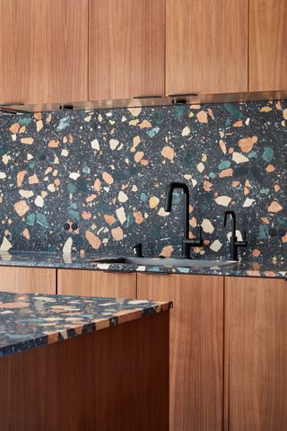 A kitchen with terrazzo backsplash against wooden panelling