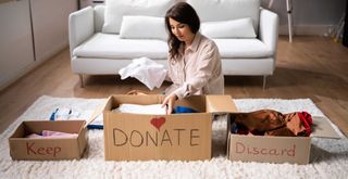 person sorting clutter into three boxes to keep, donate or discard showing how to declutter your loft as a starting point