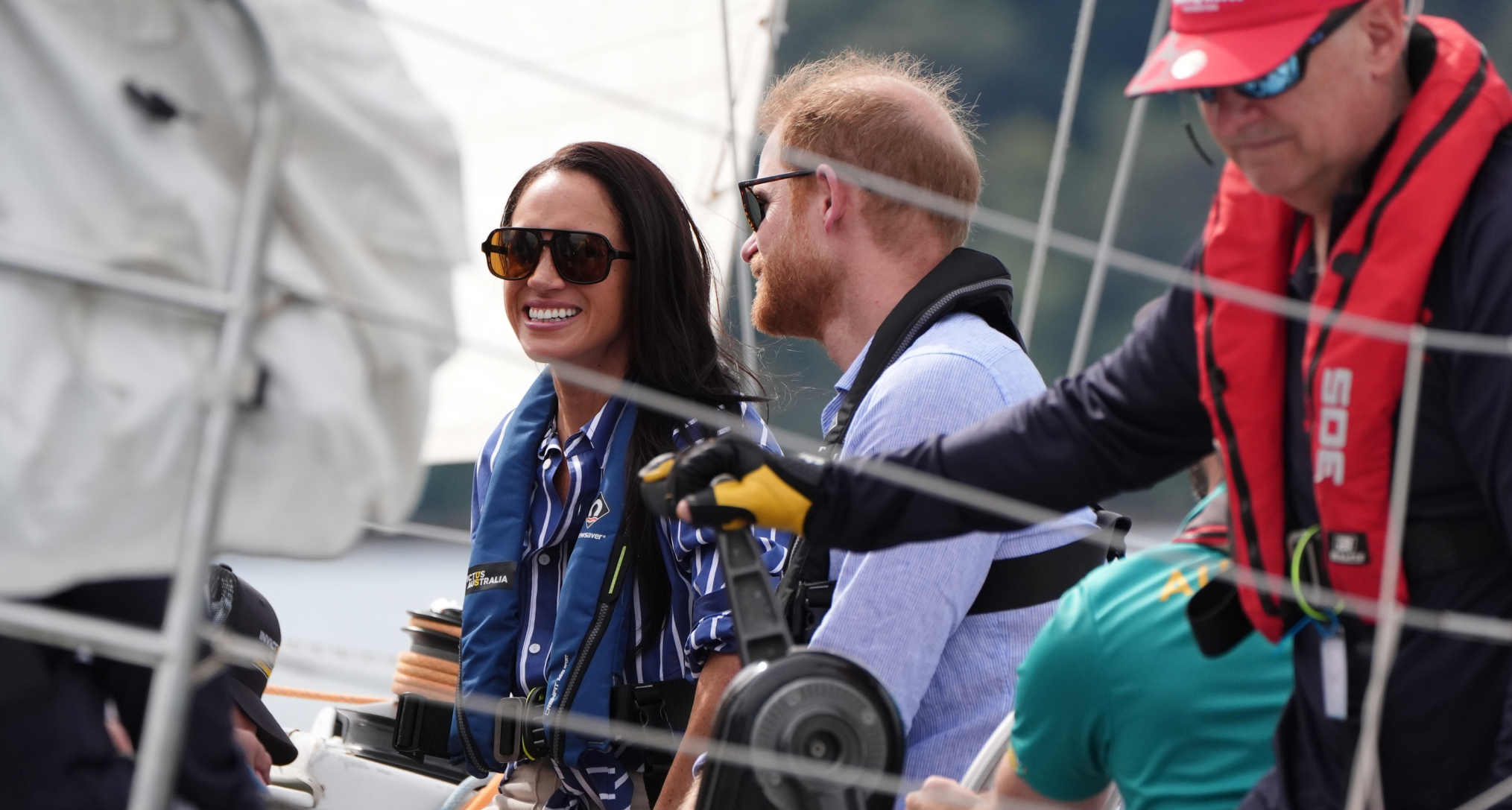 Meghan Markle and Prince Harry sitting in a boat wearing life vests and sunglasses