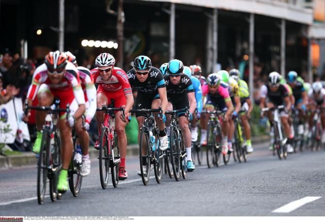 The peloton is lined out on the left of the road
