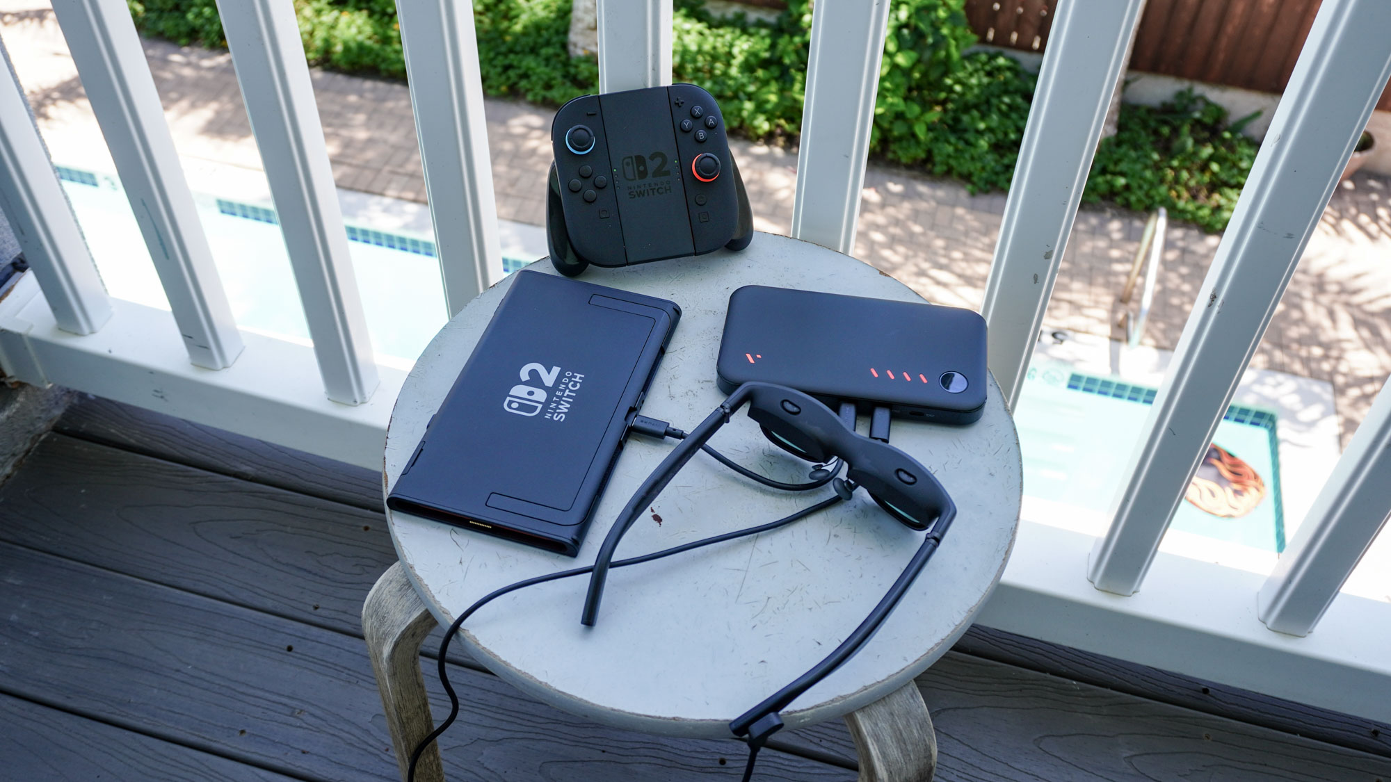 A Nintendo Switch 2 on a table outside next to the Viture Pro Mobile Dock and a pair of the Viture Pro XR glasses