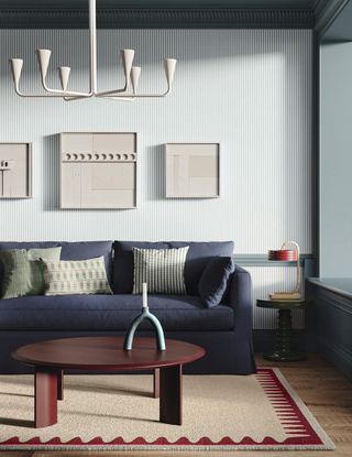 A navy sofa and a wooden coffee table on a cream and red rug