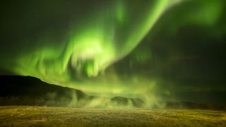 This shot shows Iceland's famous geyser, the Great Geysir, preparing to blow, with the aurora behind it.