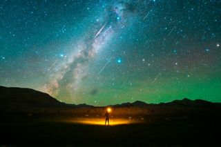 Stars and meteors can be seen in the night sky as a man watches the Perseid meteor shower on the Pamir Plateau on August 13, 2021 in Xinjiang Uygur Autonomous Region of China.