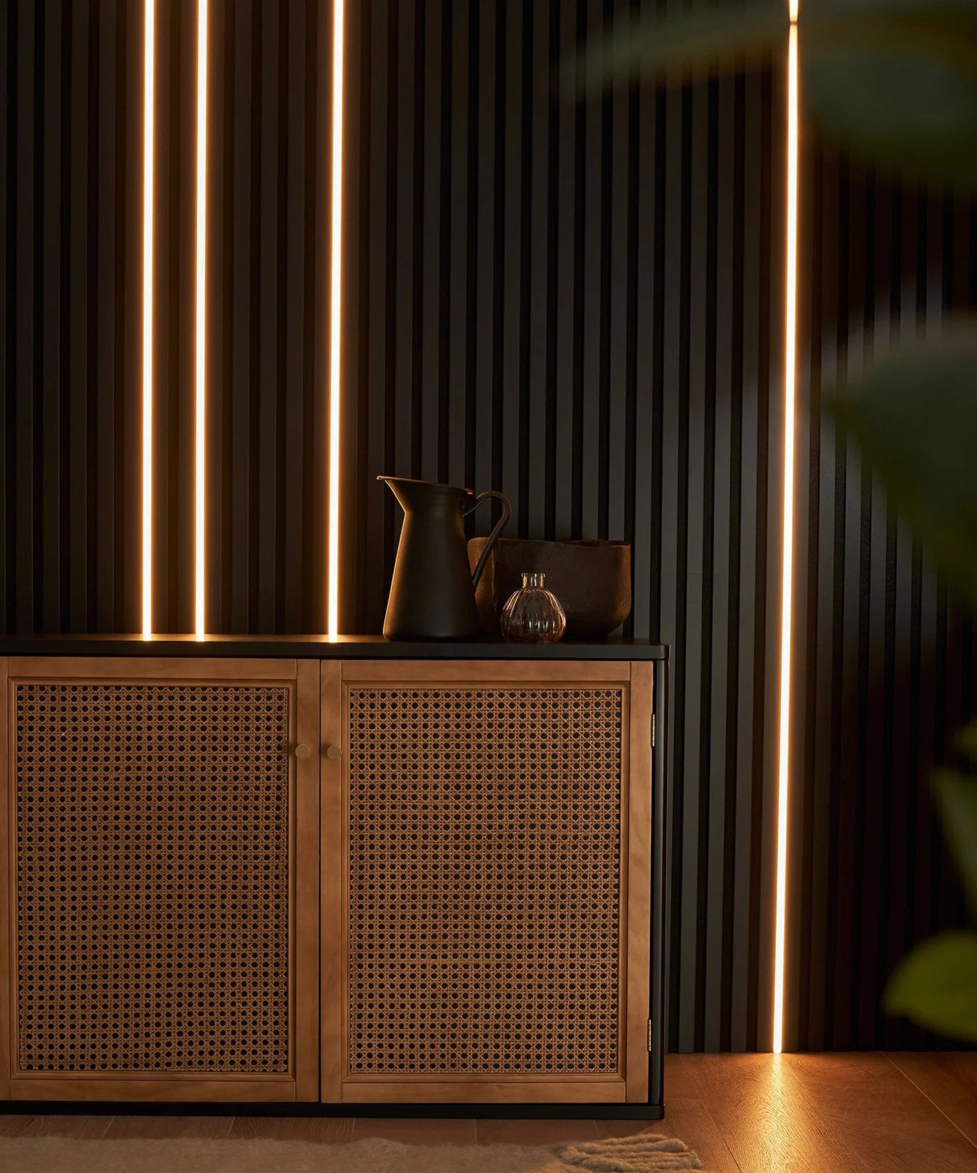 A room with black slatted vertical wall panels and LED lighting strips