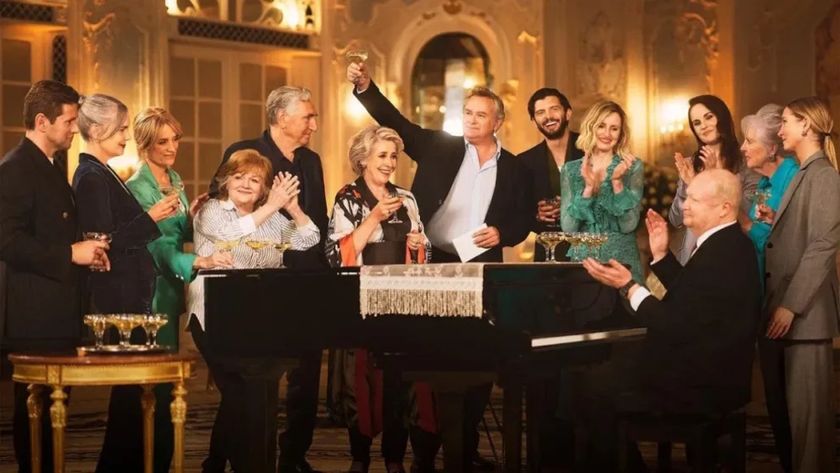 The cast of &quot;Downton Abbey&quot; standing around a grand piano and celebrating in a promotional shot for &quot;Downton Abbey Celebrates the Grand Finale&quot;