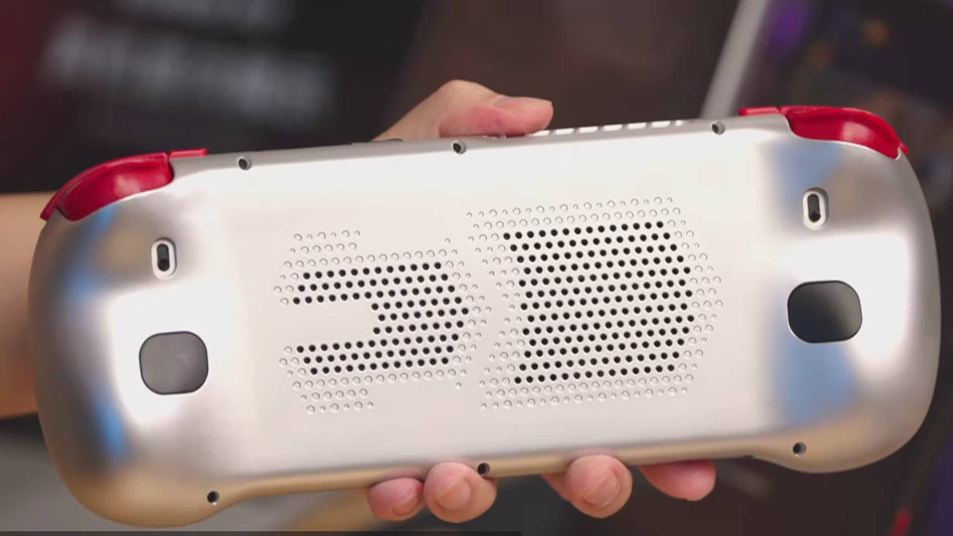 Hand holding Konkr Fit handheld with back facing camera revealing ventilation, back buttons, and adjustable trigger switches.