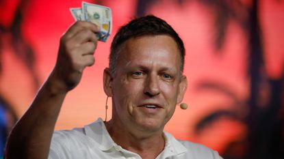Peter Thiel holds hundred dollar bills during a Bitcoin conference in Miami