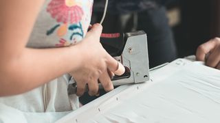 A woman using one of the best stapler guns to staple fabric