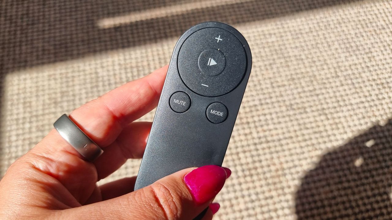 Our reviewer holding a remote control for the Urevo SpaceWalk E4W treadmill