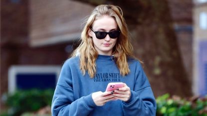 Sophie Turner wears an eras tour sweatshirt with adidas gazelle sneakers while walking in Manhattan